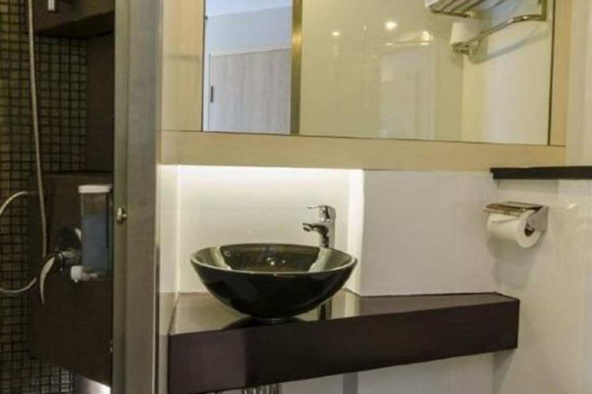 A modern bathroom with a glass bowl sink, a towel rack, and a toilet paper holder.
