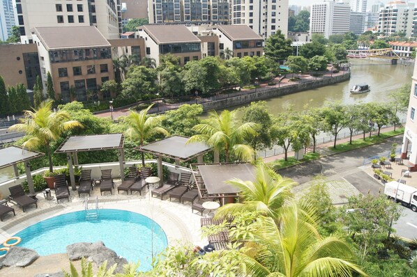 Un hôtel doté d’une piscine entourée de palmiers et de chaises longues.