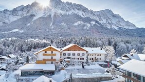 A hotel with a mountain backdrop, featuring a large building with multiple windows and a balcony. - Romantik Alpenhotel Waxenstein (Grainau)