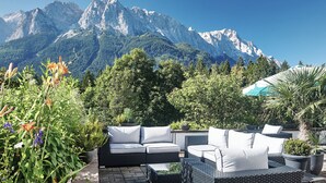 A patio with outdoor furniture, a potted plant, and a mountain view. - Romantik Alpenhotel Waxenstein (Grainau)