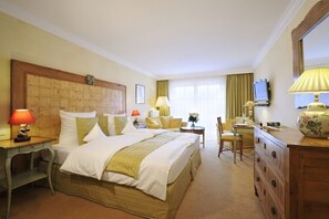 Relax in a classic hotel room with a large bed, two bedside tables, a desk, and a wall-mounted TV.