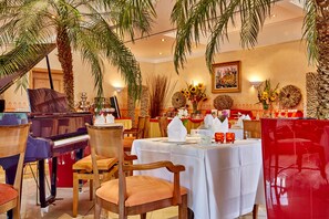 Enjoy live music and fine dining in our elegant dining area, featuring a grand piano and lush greenery.