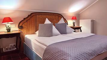 A neatly made bed with a wooden headboard, two bedside tables with lamps, and a radiator on the wall.