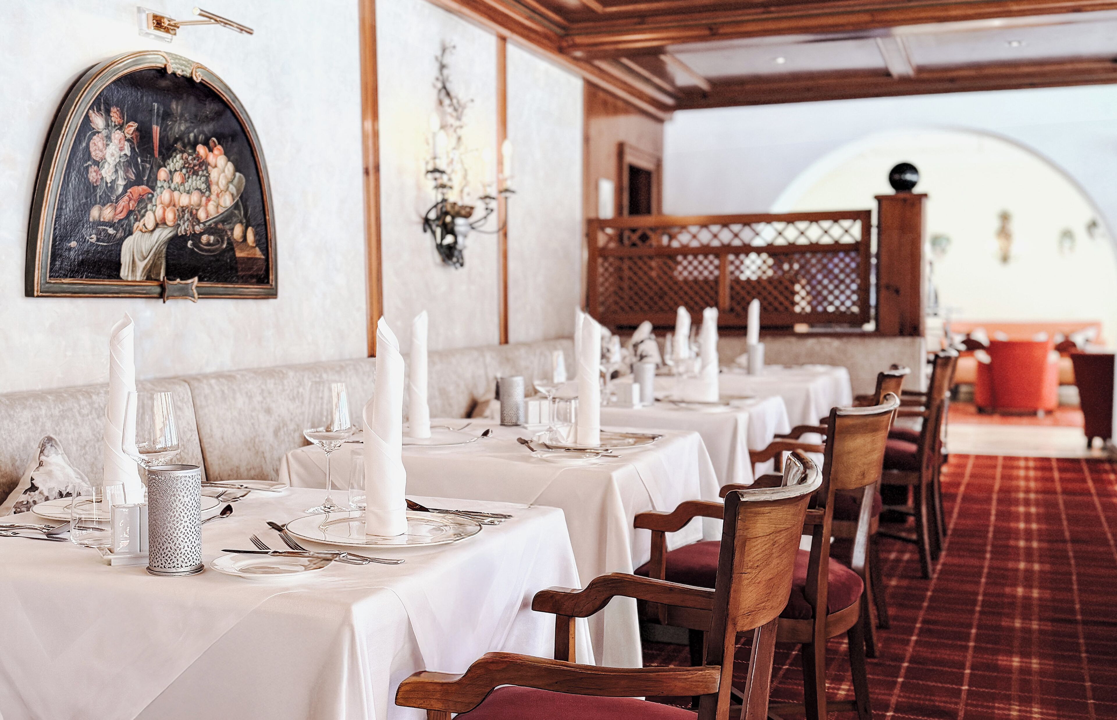 A restaurant with white tablecloths, candles, and a red carpet.