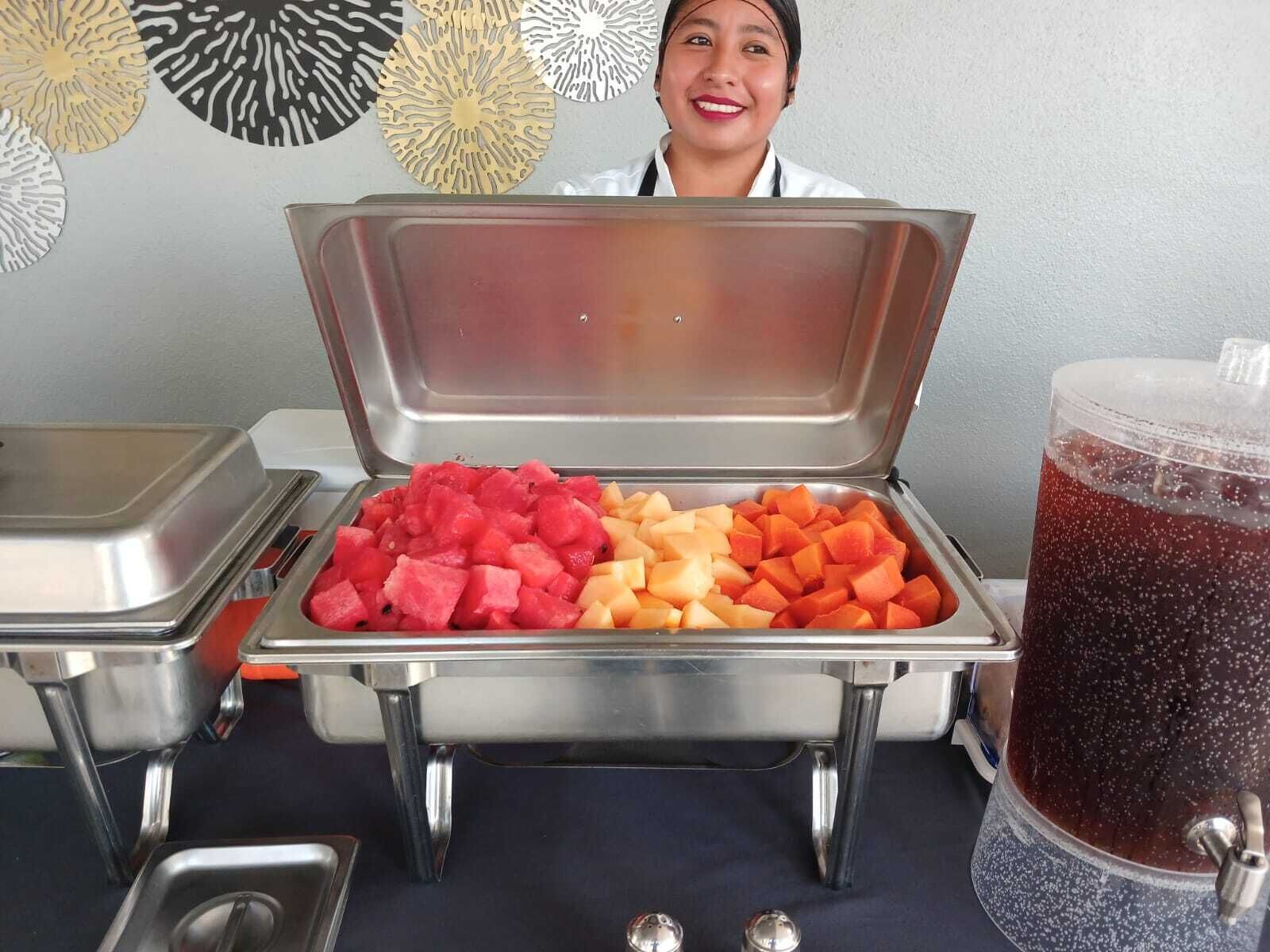 Un buffet proposant une variété de fruits et un distributeur de boissons.