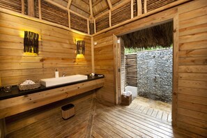 A wooden bathroom with a large sink, a mirror, and a stone wall.