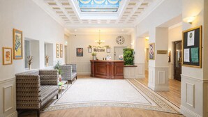 Een hotel lobby met een receptiebalie, een zithoek en een klok aan de muur.