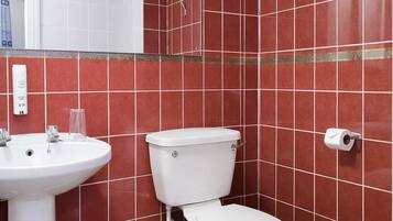 Un baño con paredes de azulejos rojos, un lavamanos blanco y un inodoro.
