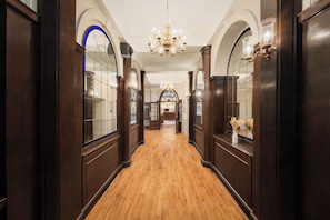 A hallway with wooden flooring, dark wood paneling, and a chandelier. - County Hotel (Carlisle)