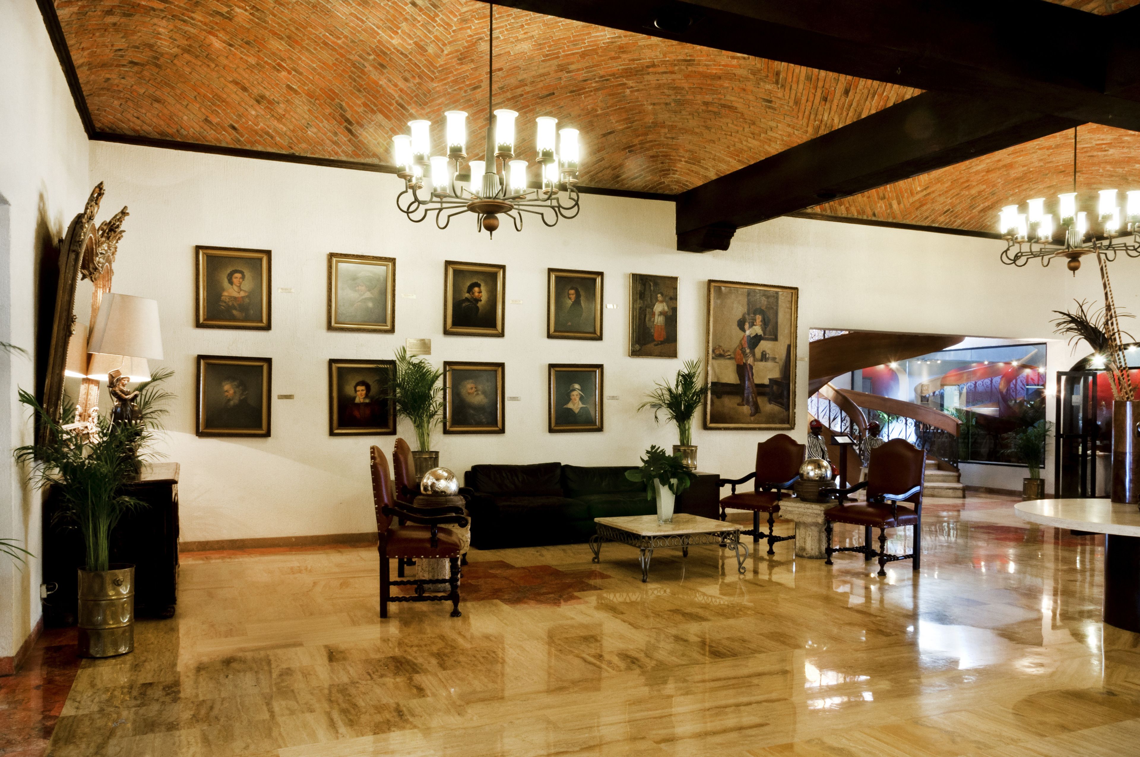 Un vestíbulo amplio con piso de madera pulida, un sofá de cuero negro y un candelabro.