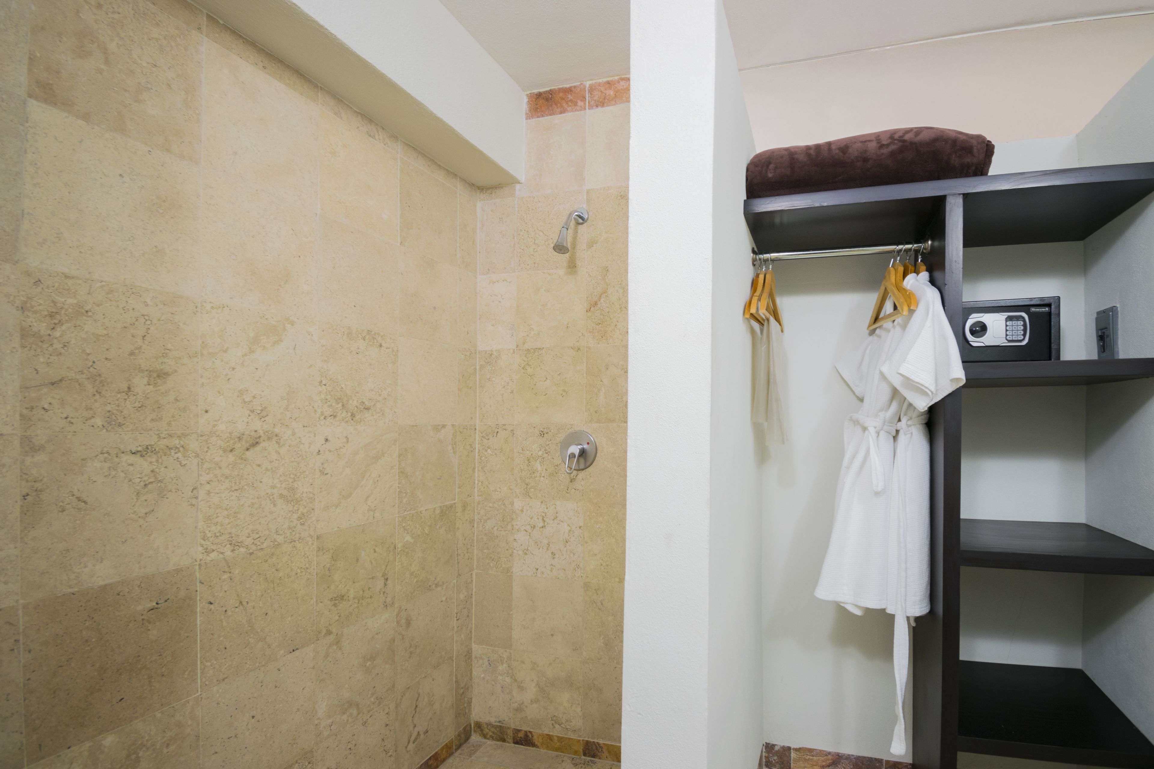 A bathroom with a shower, a towel rack with a robe, and a shelf with a radio.