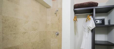 A bathroom with a shower, a towel rack with a robe, and a shelf with a radio.