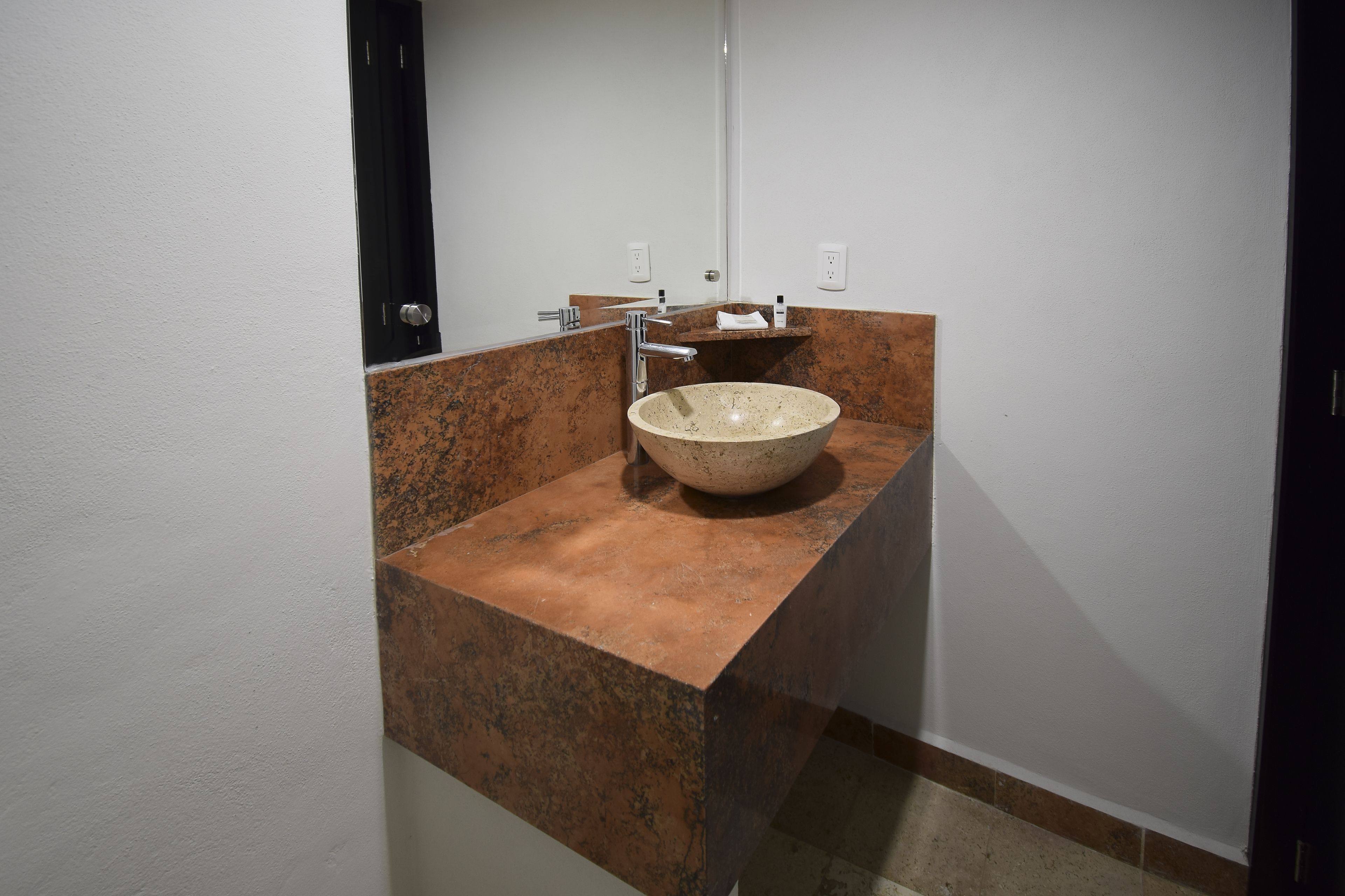 Ein Badezimmer mit einem großen Waschbecken, einem Spiegel und einem Handtuchhalter.