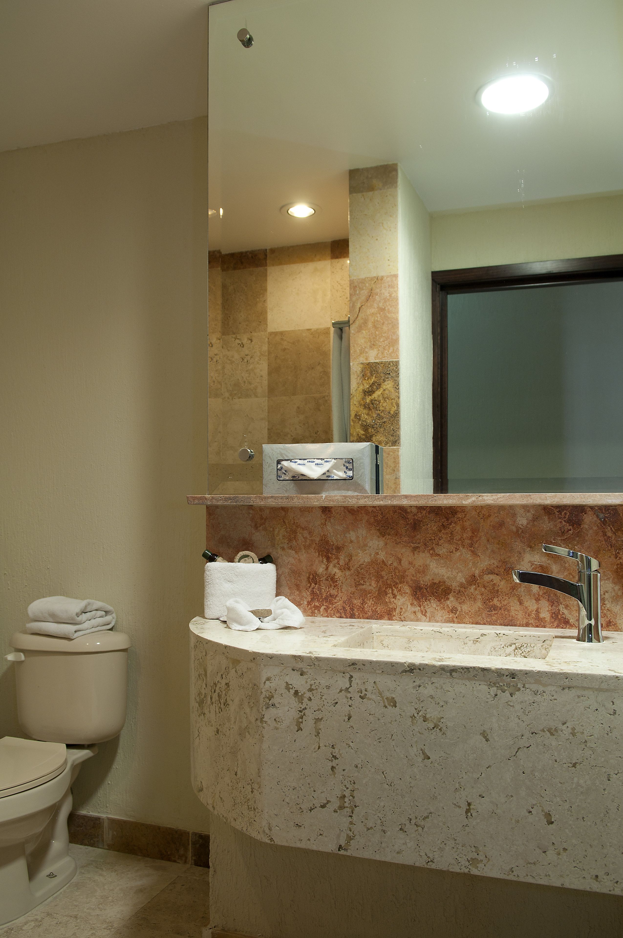 A bathroom with a marble sink, a toilet, and a mirror above the sink.