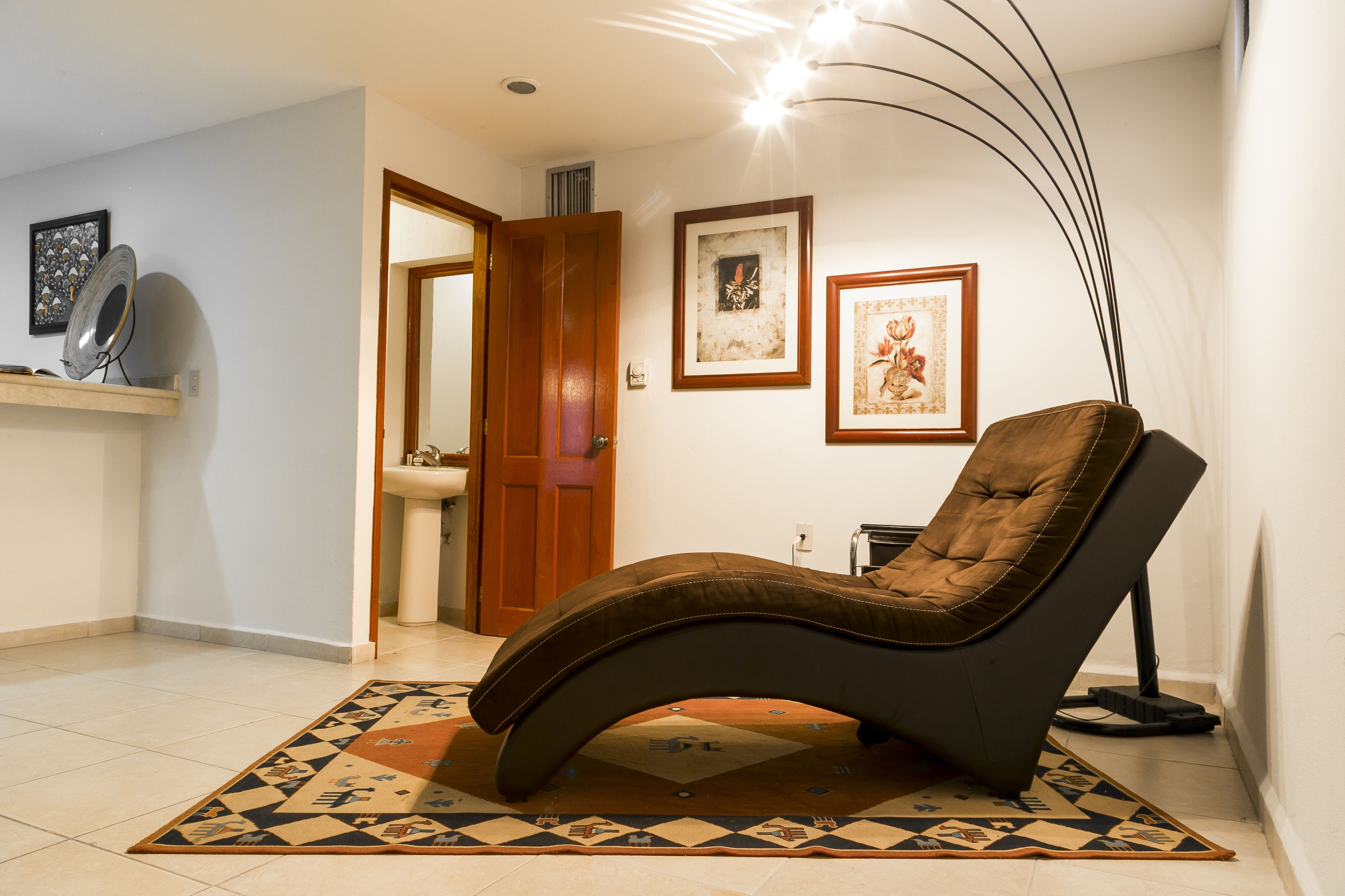 A modern living room with a reclining chair, a patterned rug, and artwork on the walls.