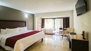 A hotel room with a large bed, a desk, a chair, a bathtub, and a TV on the wall.