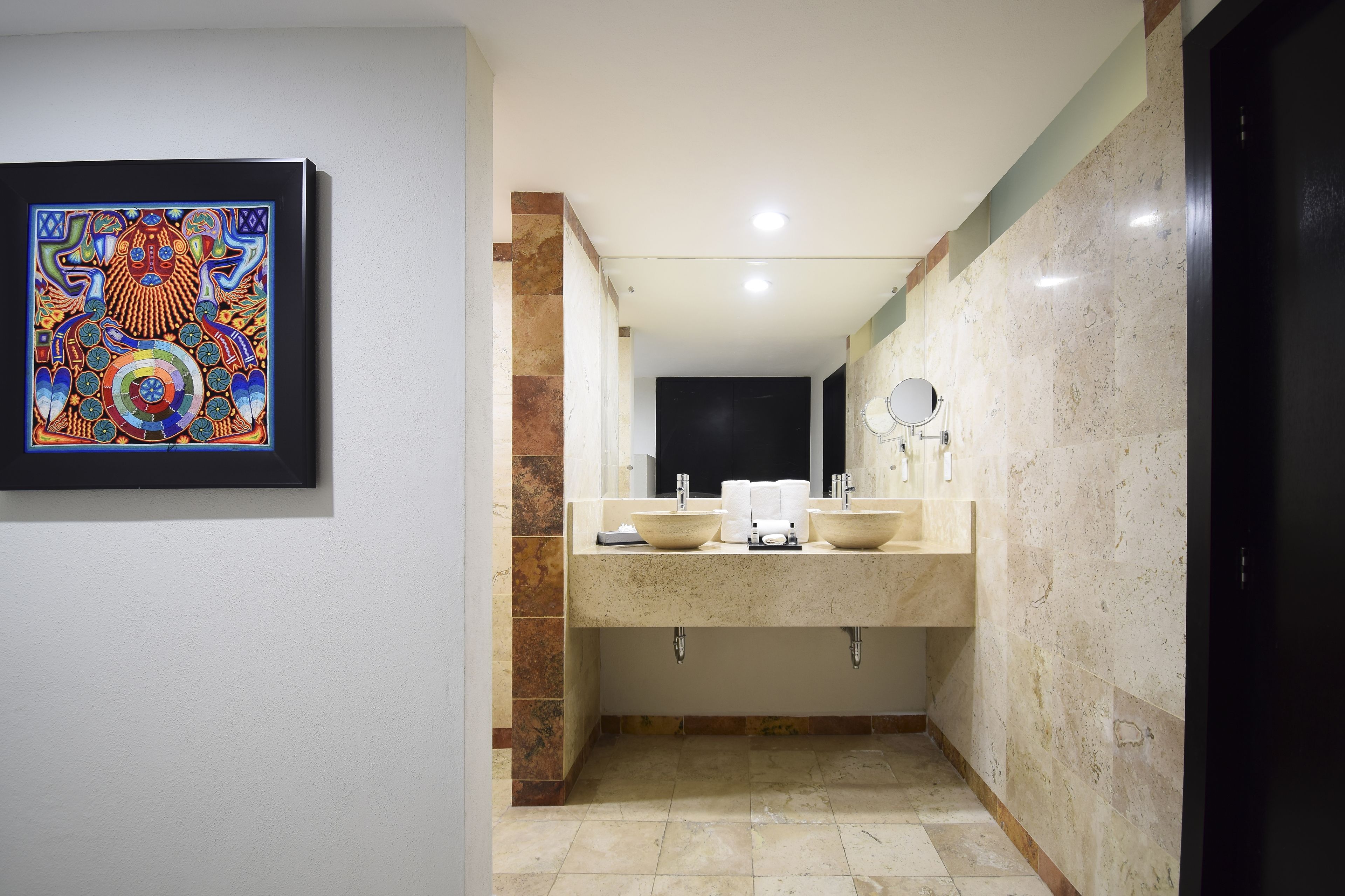 Une salle de bain moderne avec un grand miroir, deux lavabos et une œuvre d’art encadrée accrochée au mur.