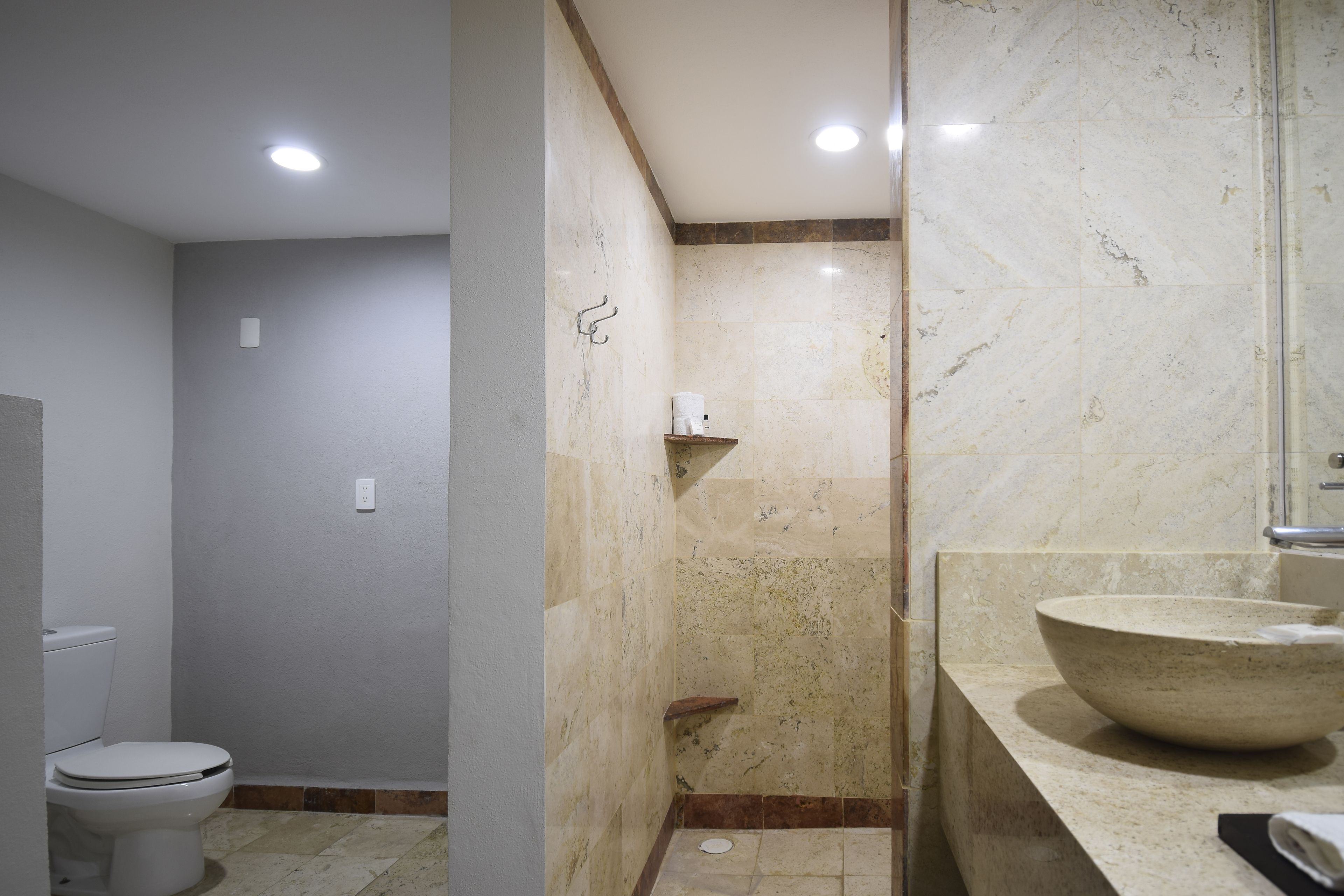 A bathroom with a toilet, a shower, and a large marble sink.
