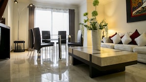 A modern living room with a sofa, a coffee table, and a dining area with chairs and a table.