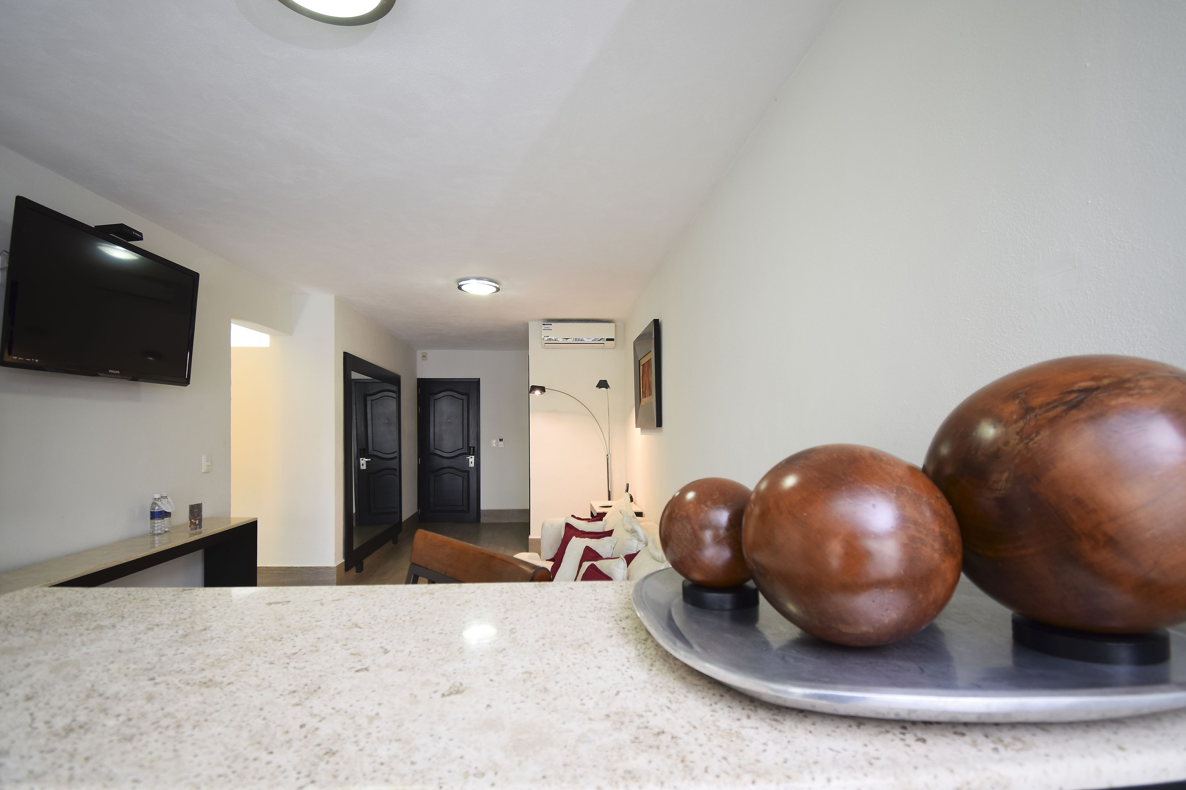 A modern kitchen with a granite countertop, a flat-screen TV mounted on the wall, and a decorative sculpture on the counter.
