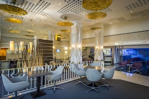 Un vestíbulo de hotel moderno con un área de estar central, un bar y una recepción.