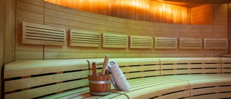 A sauna with wooden benches and a wooden bucket with a towel and a wooden mallet.