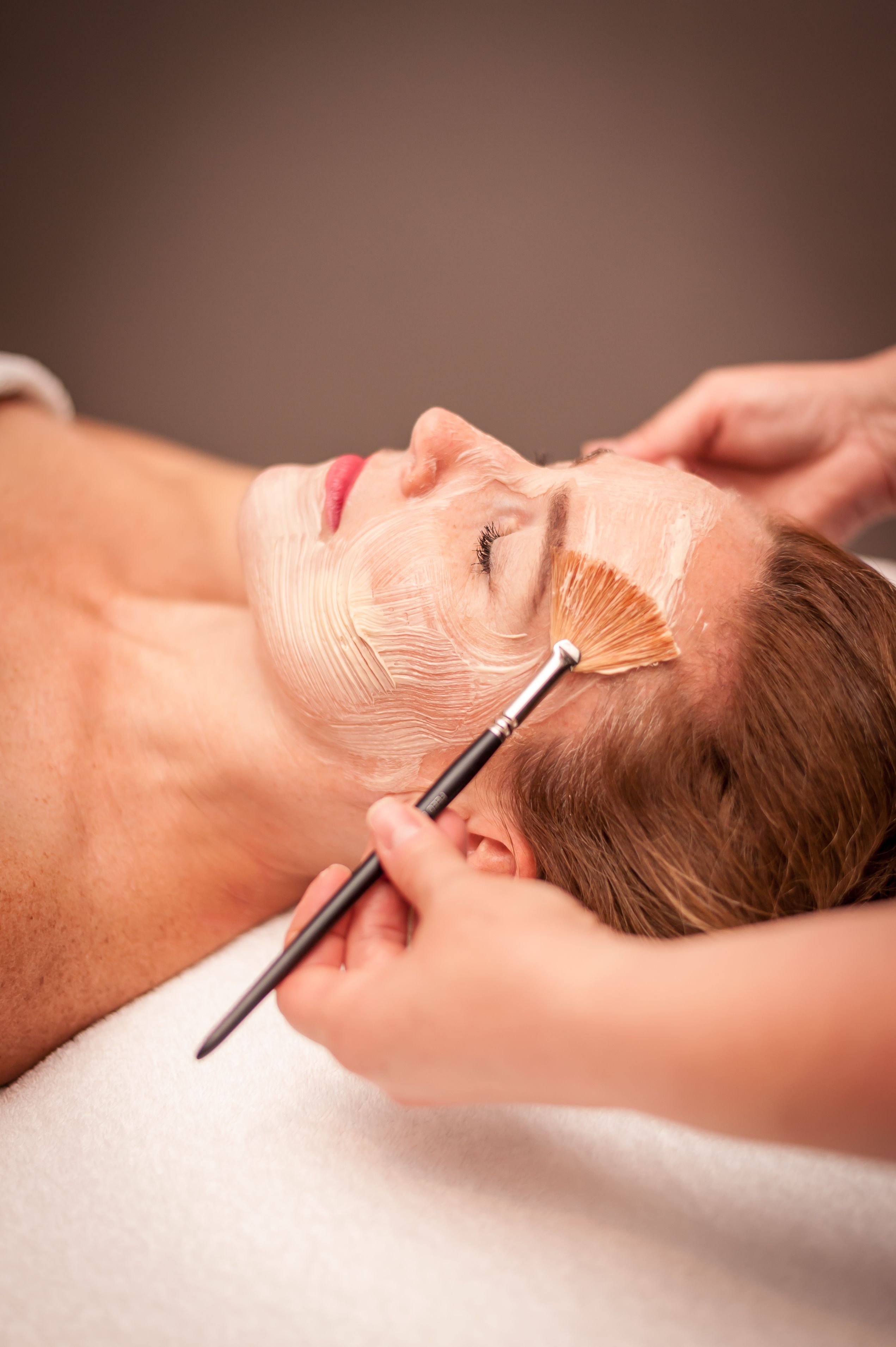 A person receiving a facial treatment with a brush.