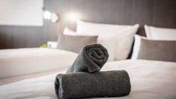 A neatly made bed with rolled towels and pillows in a hotel room.
