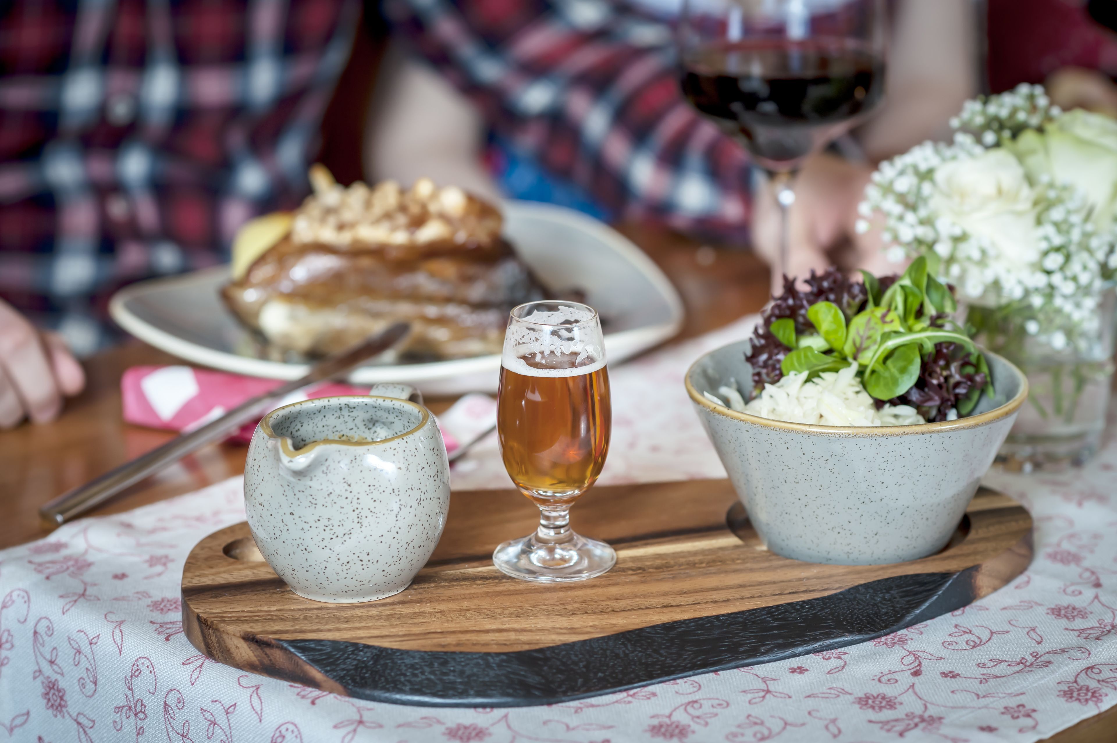 A dining table with a plate of food, a glass of beer, and a bowl of salad.