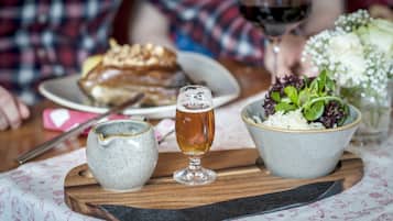 Una mesa de comedor con un plato de comida, una jarra de cerveza y un bol de ensalada.
