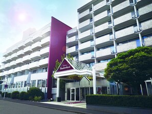 A multi-story hotel with a prominent vertical sign for Hotel Frankenland, featuring a modern architectural design with balconies and a glass entrance. - Hotel Frankenland (Bad Kissingen)