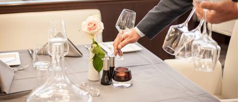 A table set for dining with clear glassware, a rose, and condiments.