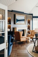 Una sala de estar moderna con chimenea, sillones de cuero, un sofá azul y un cuadro grande en la pared.