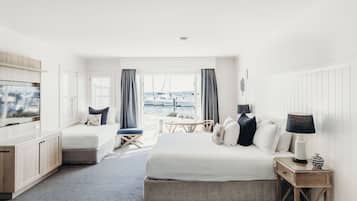 Habitación de hotel con cama, escritorio, televisión, ventana y vistas a barcos, además de una lámpara.