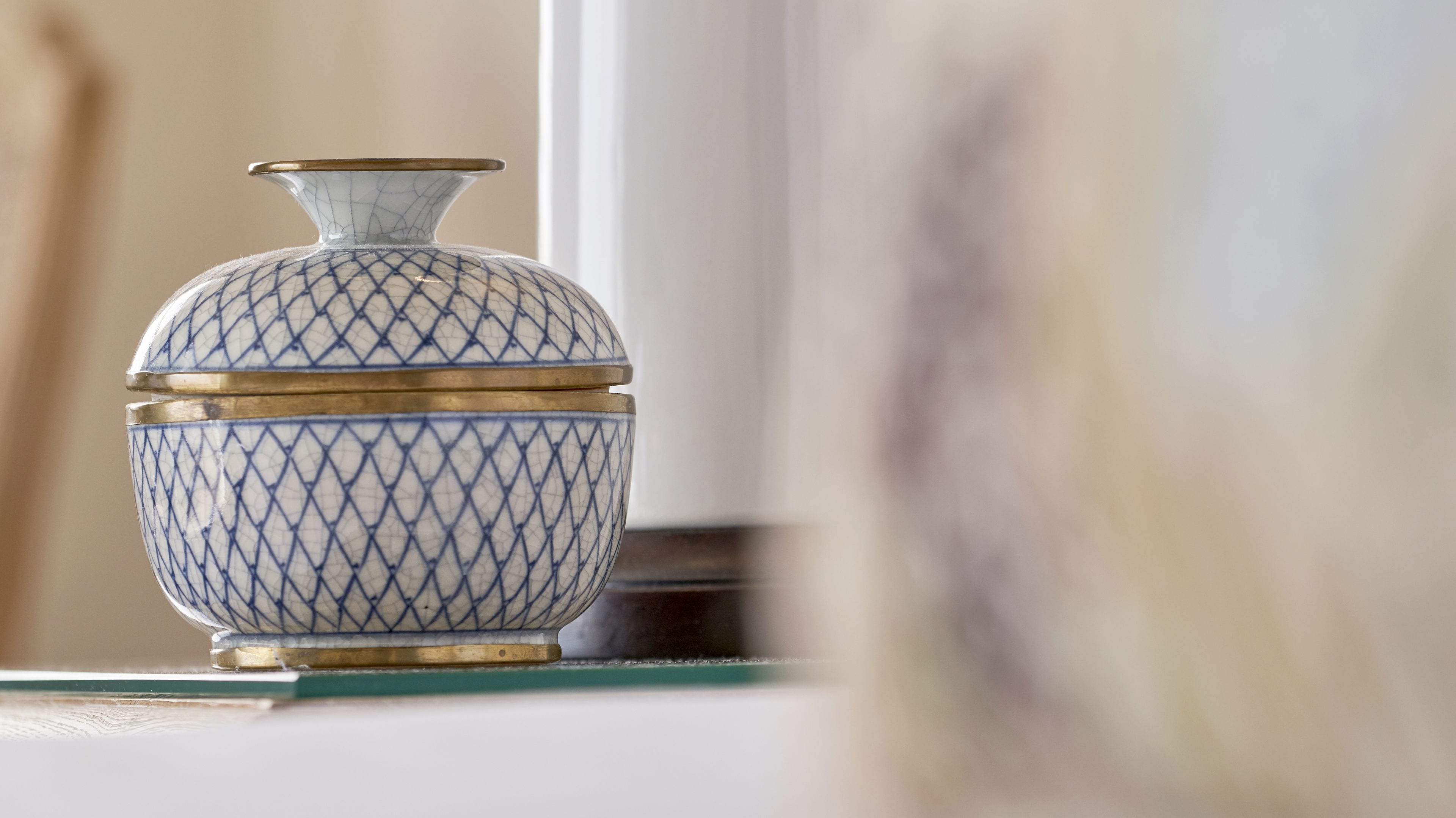 A decorative vase with a geometric pattern and gold accents, placed on a surface.