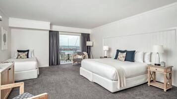 A hotel room with a large bed, a desk, a chair, and a view of the sea.