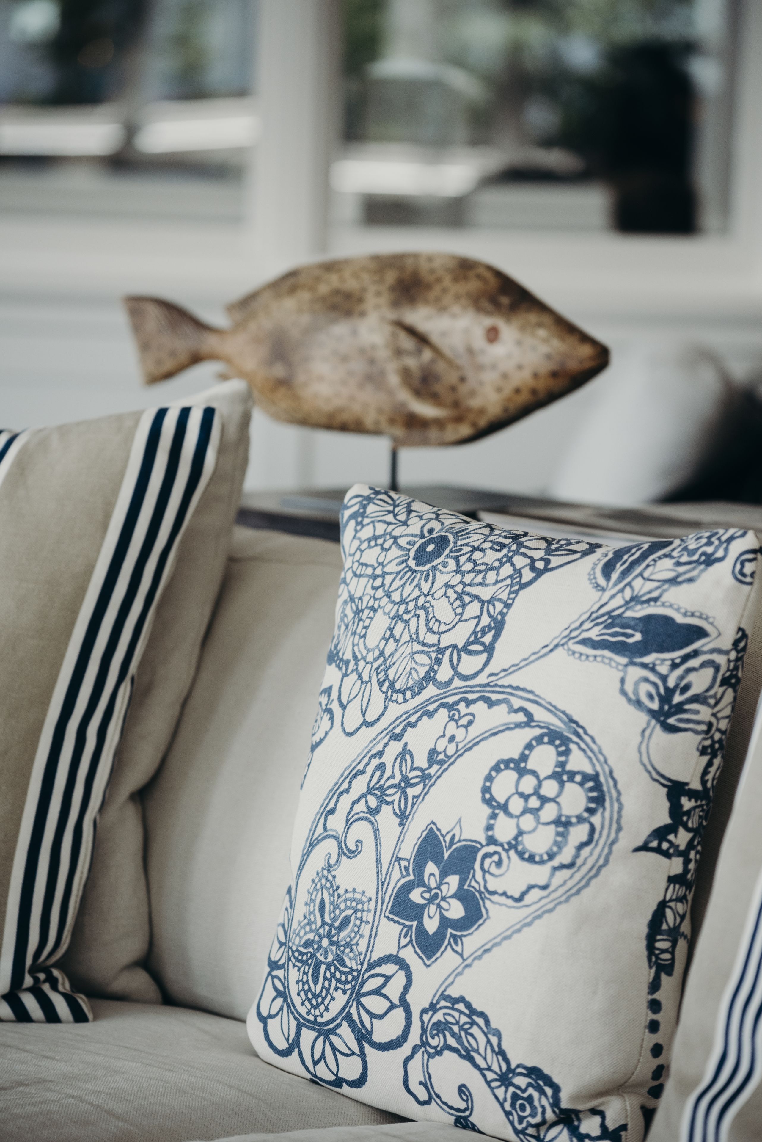 A sofa with a patterned pillow and a decorative fish ornament.