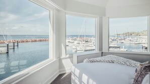 A bedroom with a large window overlooking a marina with boats and a rocky breakwater. - Anchorage Port Stephens (Corlette)