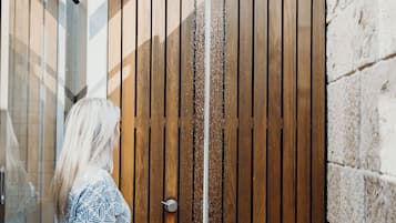 Una persona de pie frente a un portón de madera con un caño vertical.