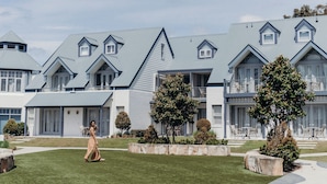 A modern hotel with a symmetrical facade, multiple balconies, and a well-maintained lawn.