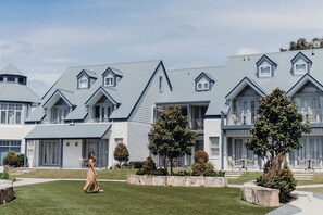 A modern hotel with a symmetrical facade, multiple balconies, and a well-maintained lawn.