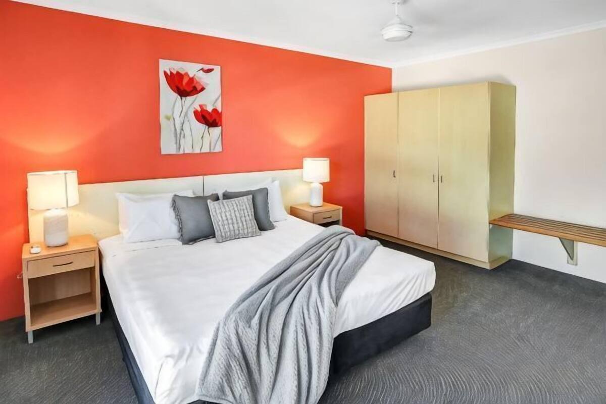 A hotel room with a bed, nightstands, a wardrobe, and a wall art piece.