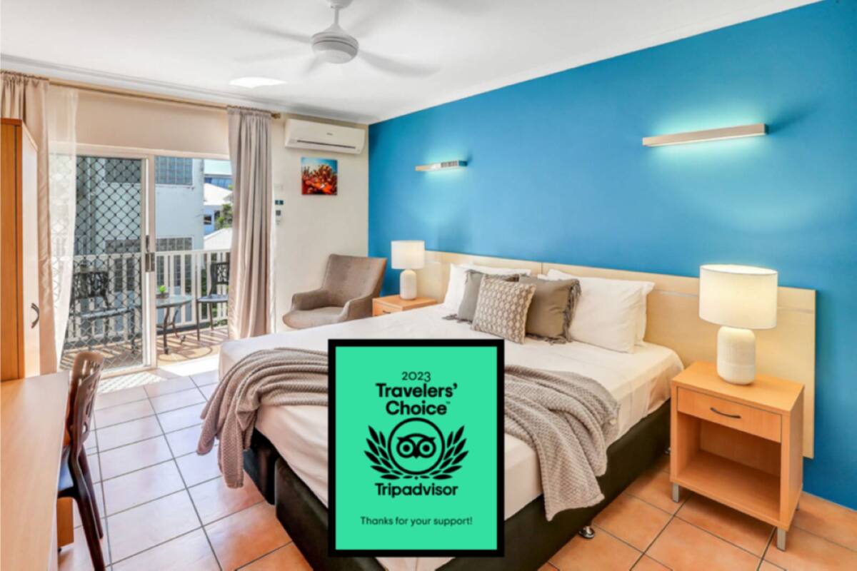 A modern hotel room with a large bed, two bedside tables with lamps, a chair, and a balcony with a view.