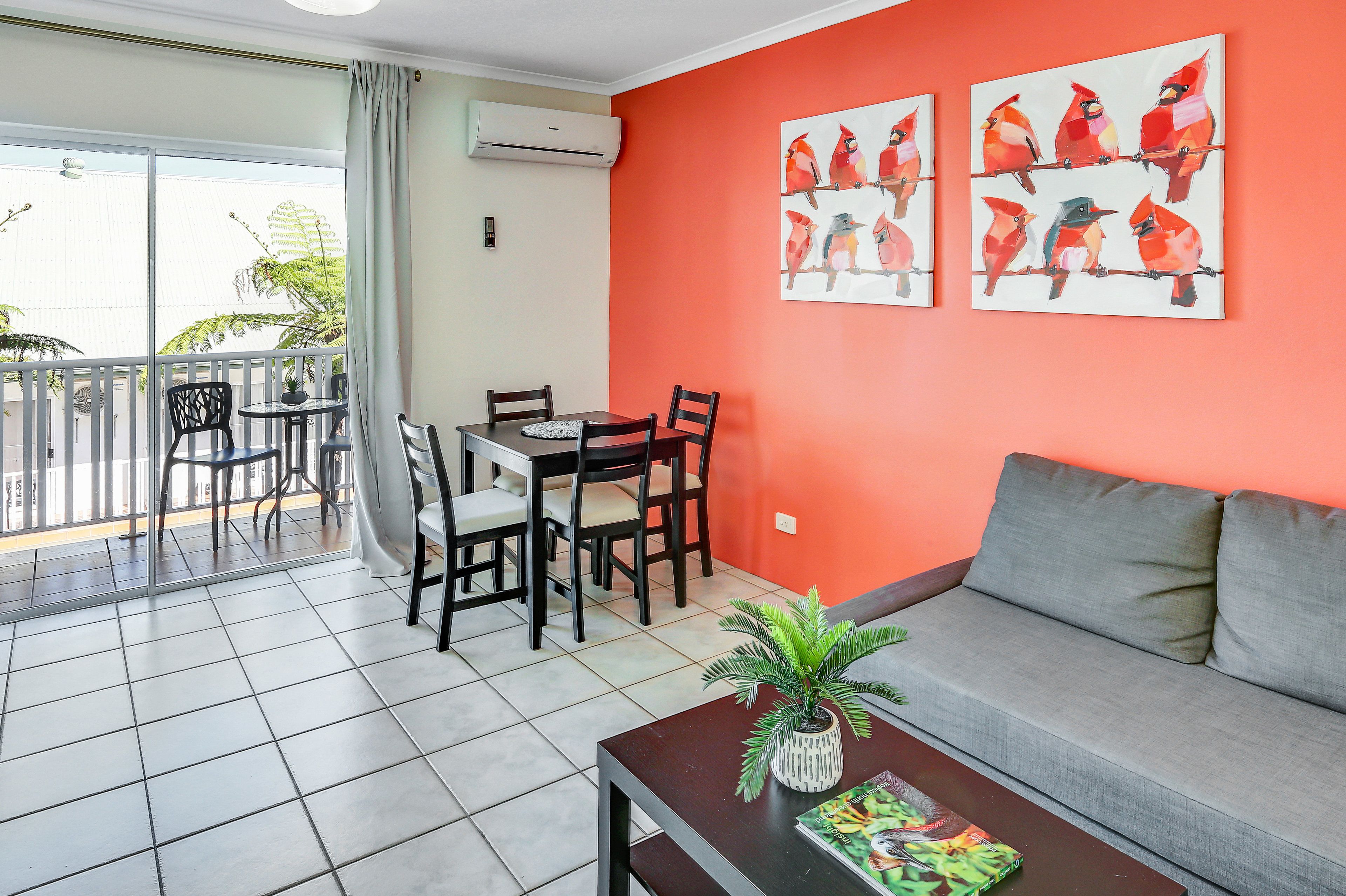 A room with a dining area, a sofa, and a balcony with a view.