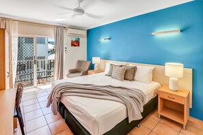 A bedroom with a bed, bedside tables, a chair, and a view of a balcony.