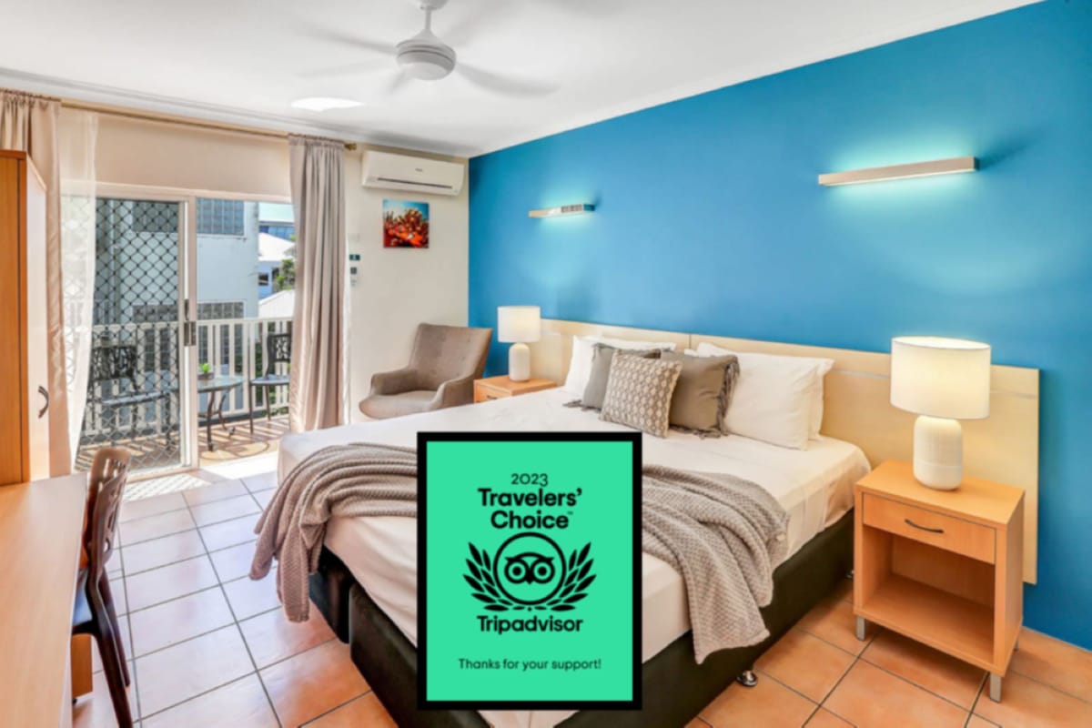 A modern hotel room with a large bed, two bedside tables with lamps, a chair, and a balcony with a view.