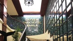 A staircase leading to a room with a view of the city, a chandelier, and a sign for Bayview Park Hotel Manila. - Bayview Park Hotel Manila (Manila)
