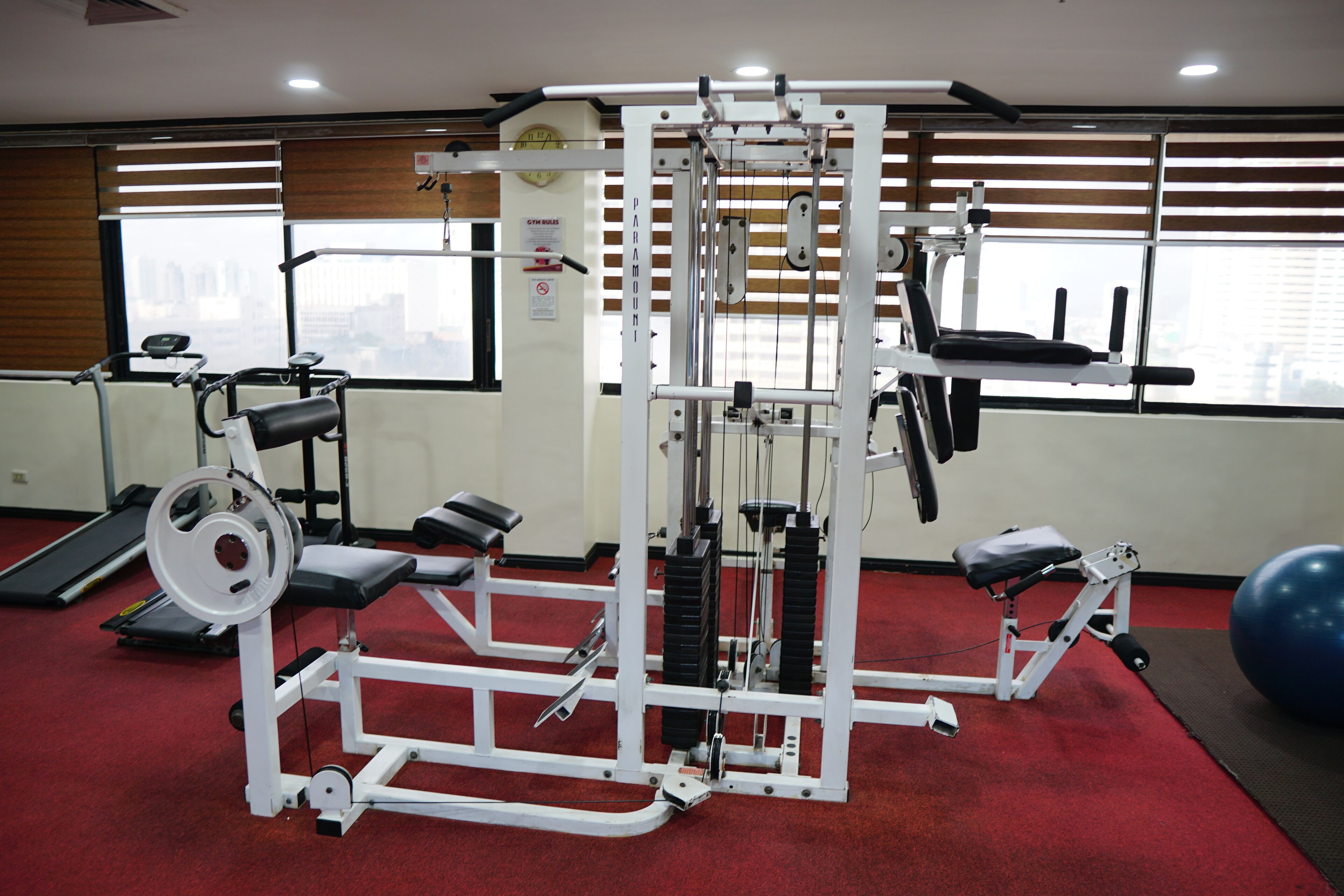 Un gimnasio con máquinas de pesas, una cinta de correr y pelotas de ejercicios.