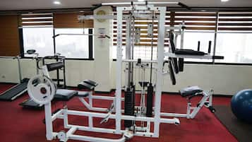 Un gimnasio con máquinas de pesas, una cinta de correr y pelotas de ejercicios.