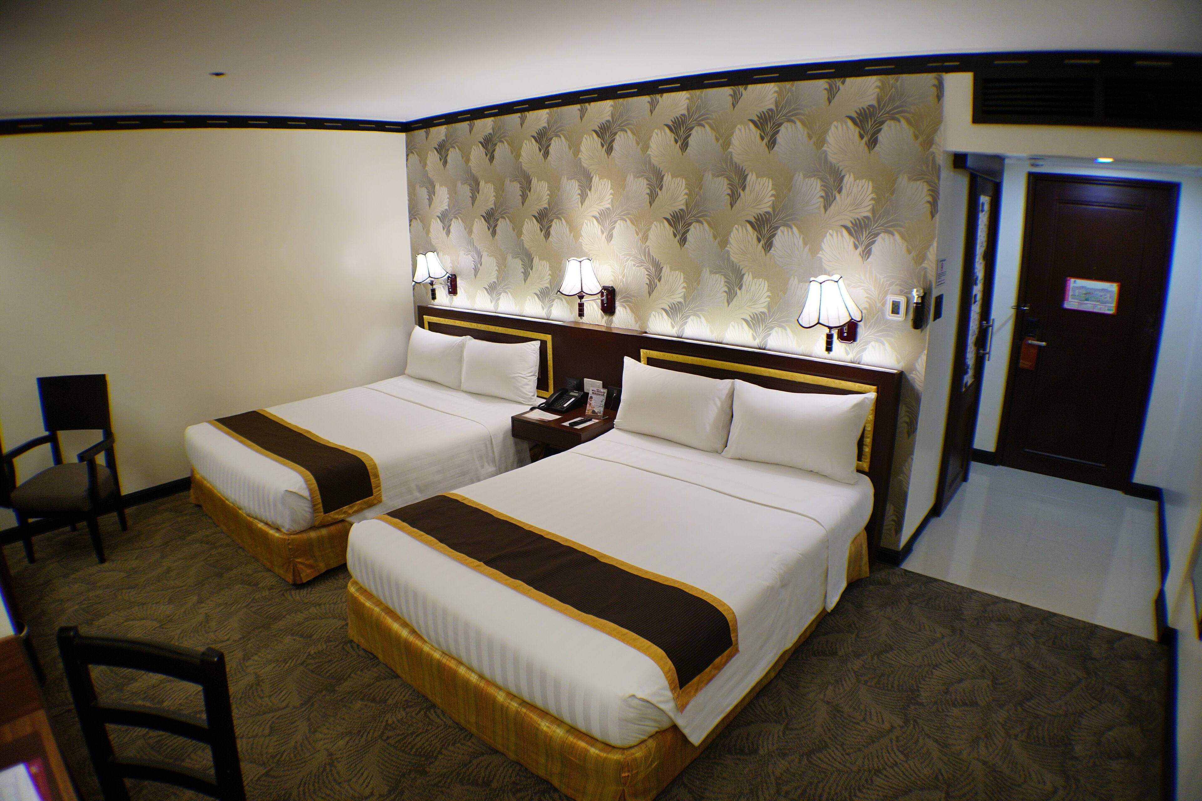 Habitación de hotel con dos camas, un escritorio, una silla y una puerta.